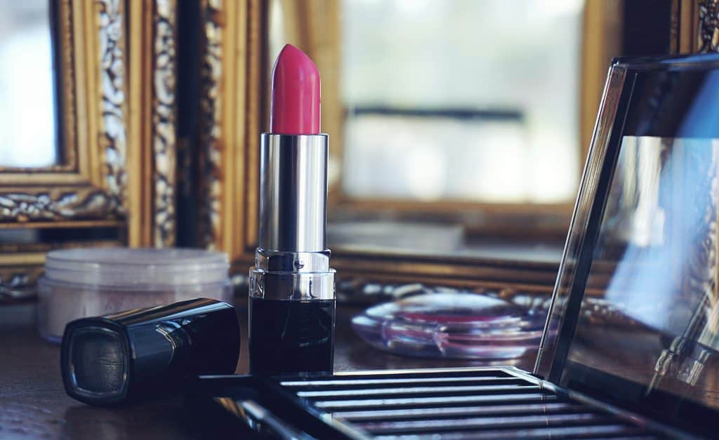 Elegant close-up of pink lipstick on a stylish makeup vanity with reflections.